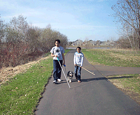 Maya understands blindness and Jordan�s use of the white cane in a way that only an adoring little sister can. Here she joins Jordan as he walks the family dog, and carries her own makeshift cane. 