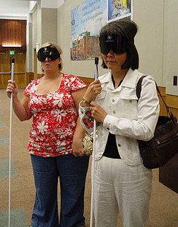 Jennifer Hu (VA), far right, listens carefully to instructions as she gets ready for her sleepshade cane travel experience.