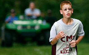 A young boy runs a cross country race.