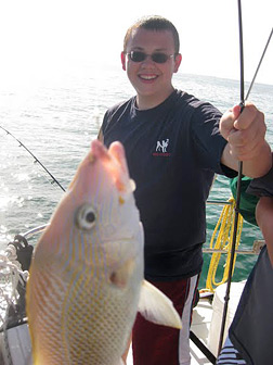 Eric Marten holds a fishing pole with a huge fish on the line.