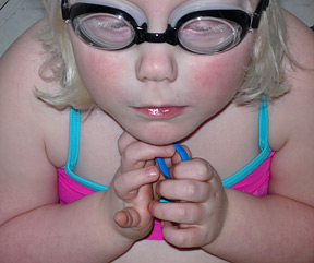 Closeup of Elizabeth in a swimsuit, wearing goggles.