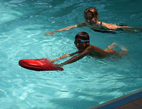 student practices his kick in the pool while holding a float at arm’s length. Check out 'Picturing Convention.'