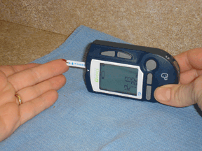Figure 1 - While keeping your fingertip facing up to keep the blood drop from sliding to the side, move the meter or your finger so that the bottom left corner of the strip touches the fingertip. 
