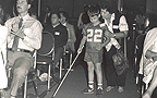 Blind boy with cane walks down convention aisle with mother