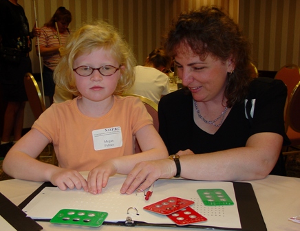 Young student reading Braille with her instructor.