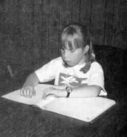 A picture of a nine or 10-year-old girl, Ellen Bartley, reading a book seated at a desk.