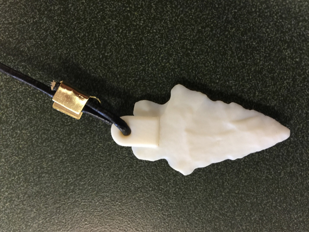 Close-up picture of a 3D-printed point. A leather
lanyard is attached to the 3D-print through a hole drilled in it. The
other end of the lanyard is similarly attached to the wooden coin and
QR-code.